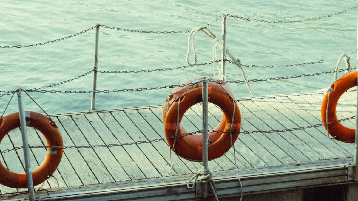 Three life rings hang on a dock by the tranquil sea, providing a sense of safety and readiness.