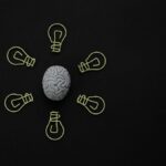 Conceptual photo of a brain surrounded by light bulb clips on black background.