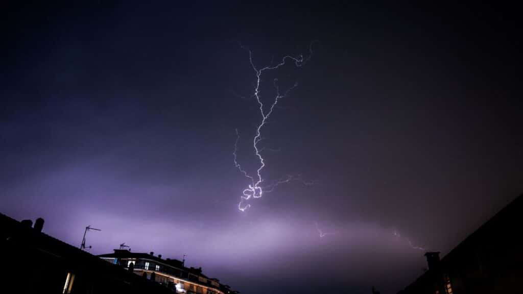 Captivating lightning bolt during a nighttime thunderstorm over silhouetted cityscape.