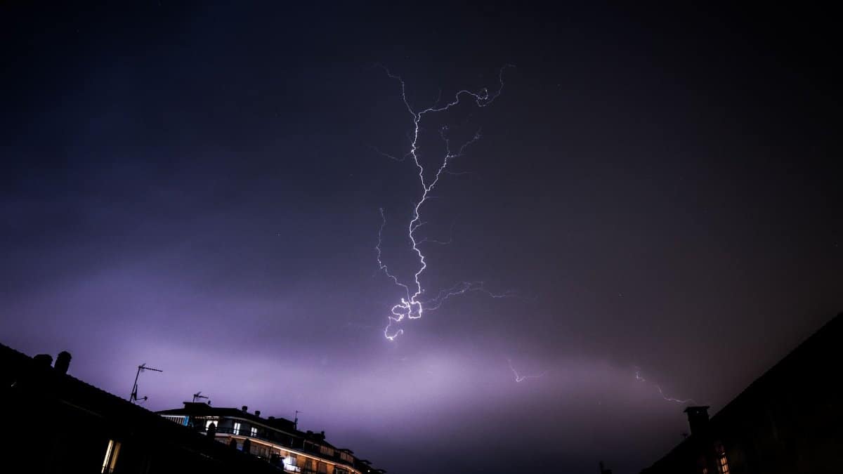 Captivating lightning bolt during a nighttime thunderstorm over silhouetted cityscape.
