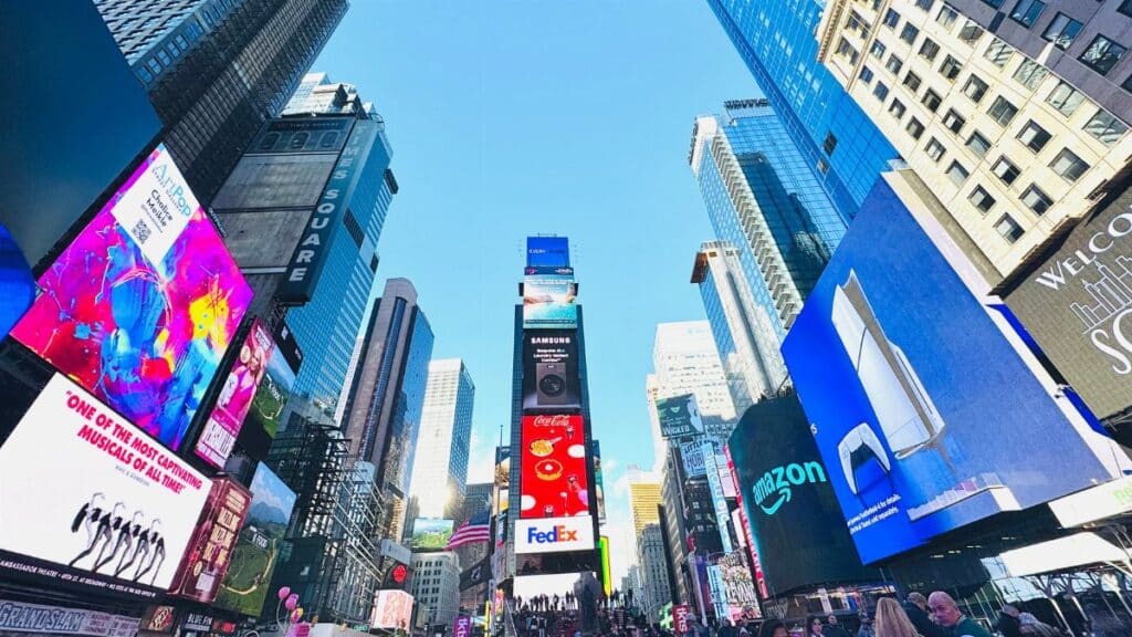 Vibrant daytime view of Times Square, showcasing iconic billboards and bustling crowd in New York City.