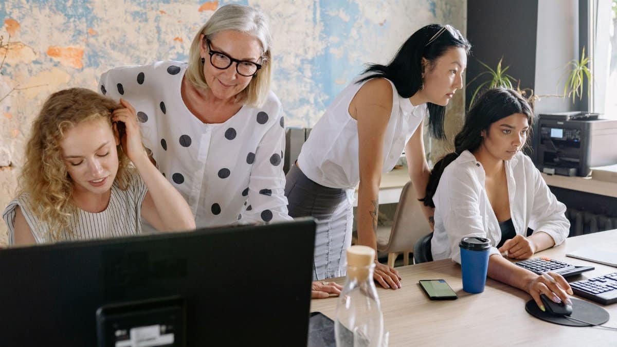 A group of women collaborating in a contemporary office setting, engaging in teamwork and discussion.