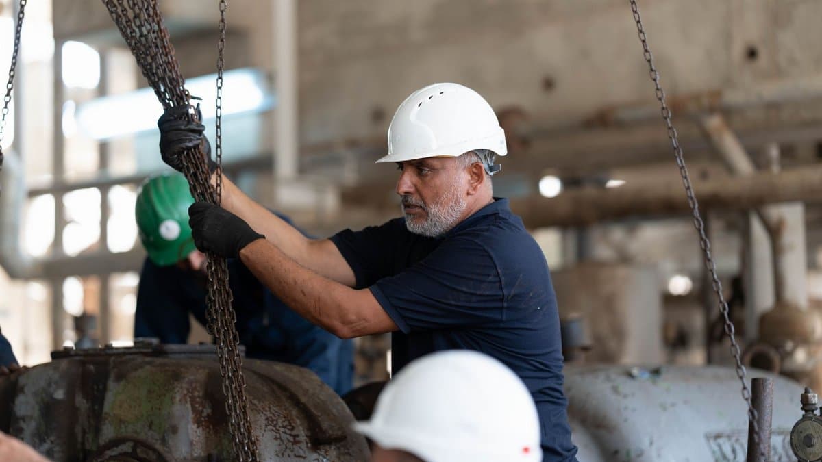 Workers with helmets operating chains in an industrial setting, Libya.