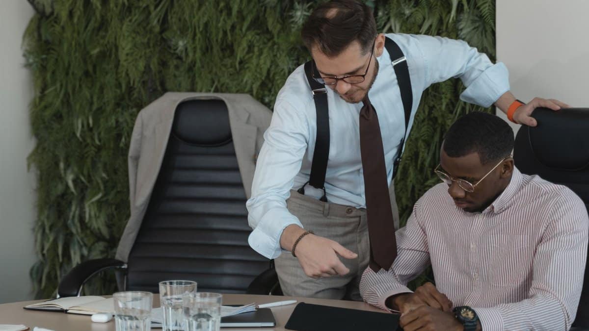 Two businessmen engaged in a collaborative office discussion, using a tablet.
