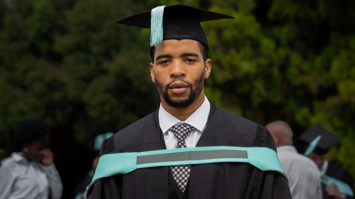 A young man in a graduation gown and cap poses outdoors in Pretoria.