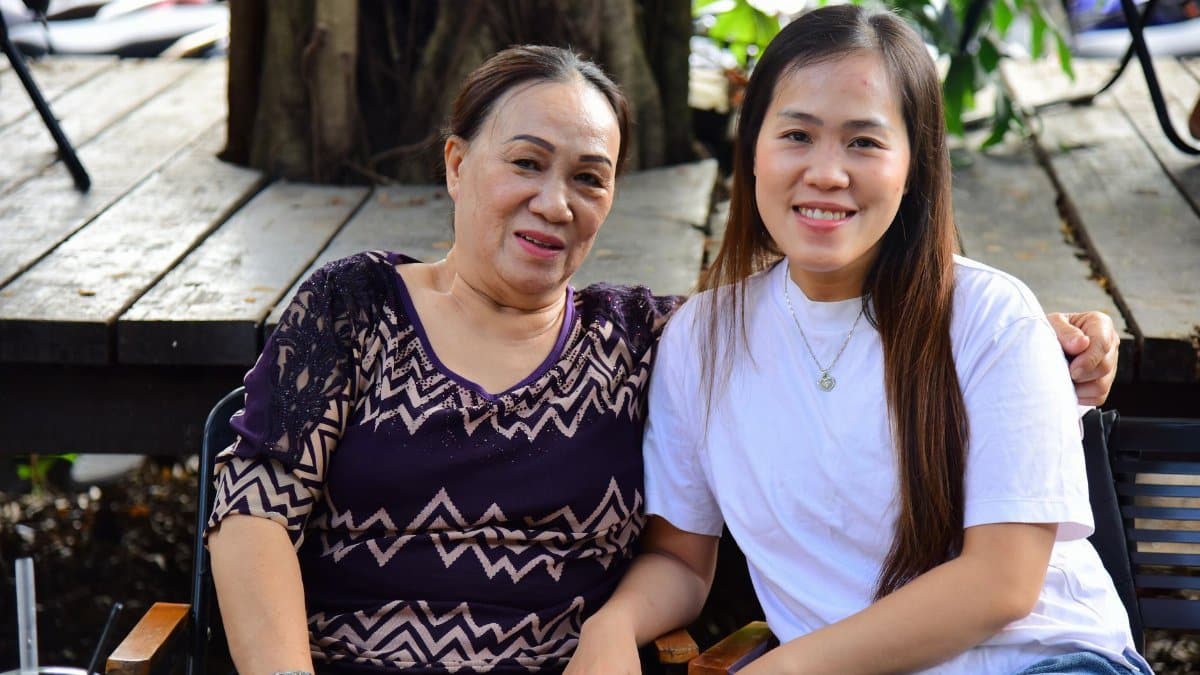 Happy older and younger woman sitting together outdoors, showcasing family bond.