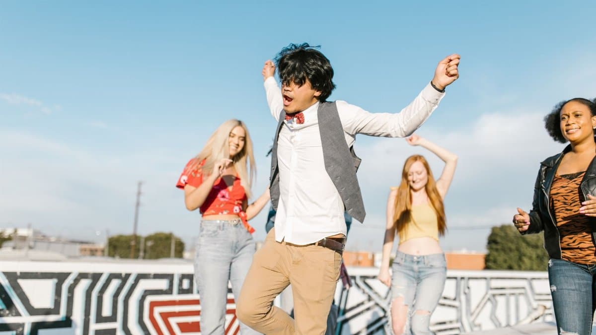 Young adults enjoying a vibrant rooftop dance party under a clear blue sky.