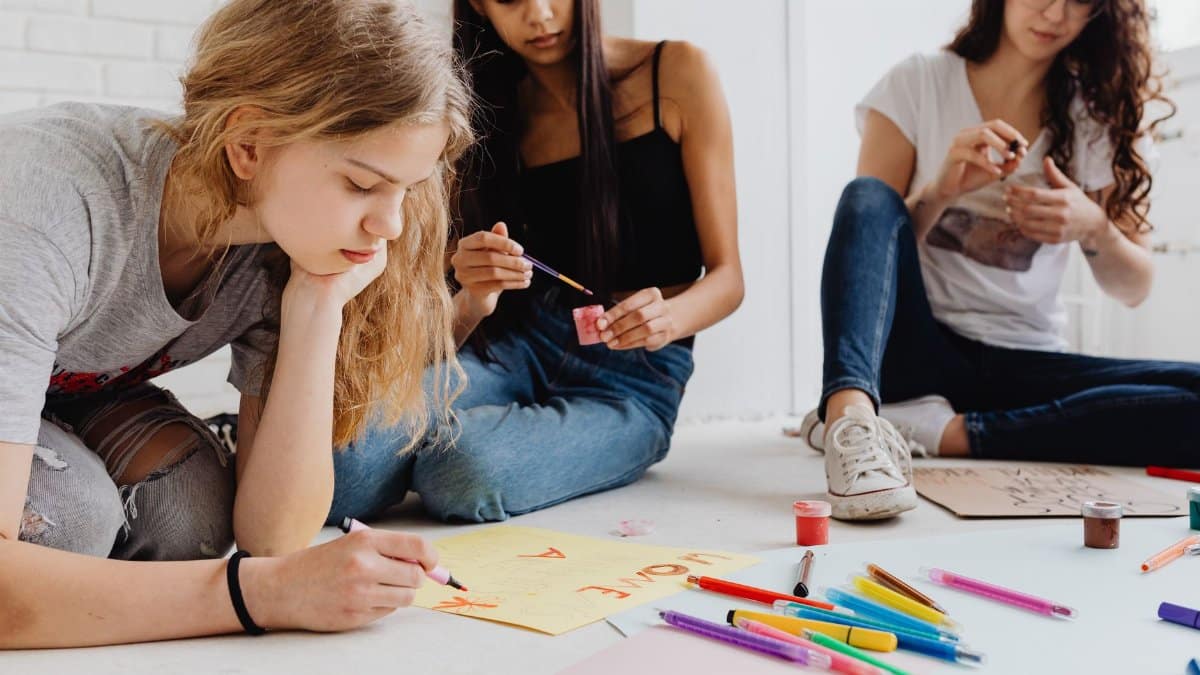 Teenagers collaborating on art projects using paints and pencils, promoting creativity and teamwork.