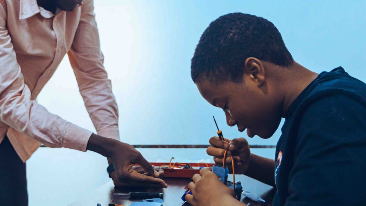 A student and a teacher engage in practical electronics learning in a classroom environment.