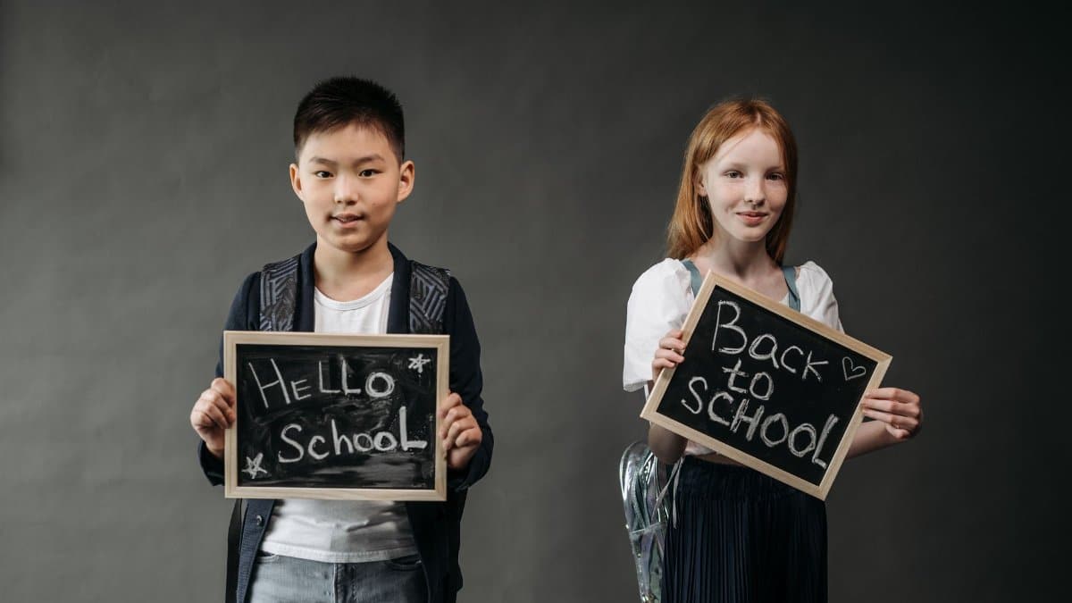 Two smiling students holding chalkboards with back to school messages.