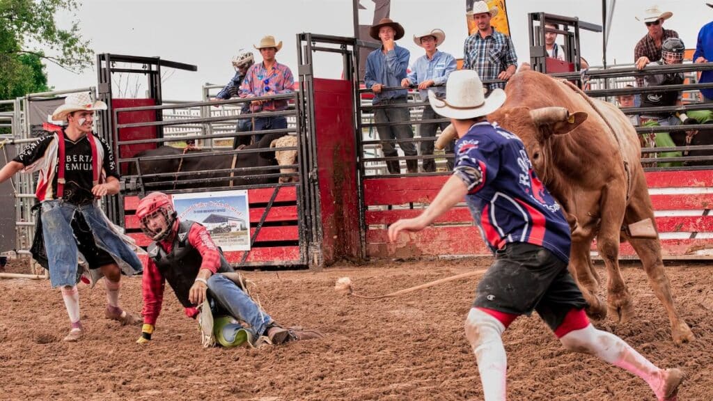 Dynamic rodeo scene with bull riders and clowns in action, capturing the excitement of the event.