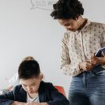 A teacher guides a student in a classroom, fostering an environment of learning and support.