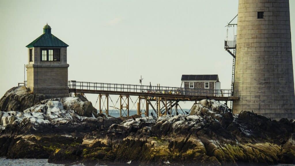 A scenic view of a lighthouse on rocky shores in Boston, MA.