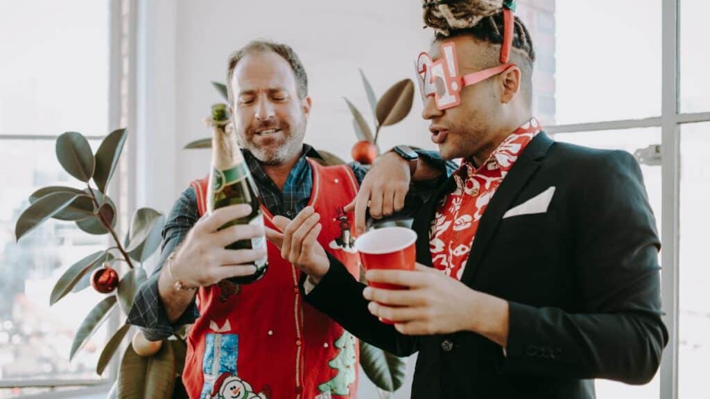 Two men celebrate in holiday style with champagne and festive attire.
