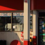 Convenience store entrance at a gas station featuring lottery signs in Bridgeton, New Jersey.