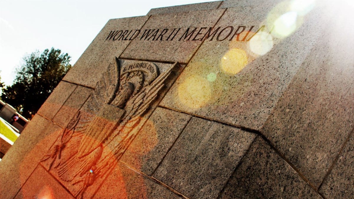A striking view of a World War II memorial with lens flare enhancing its historic significance.