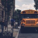 A school bus parked on a city street with pedestrians and a SEPTA bus in Philadelphia.