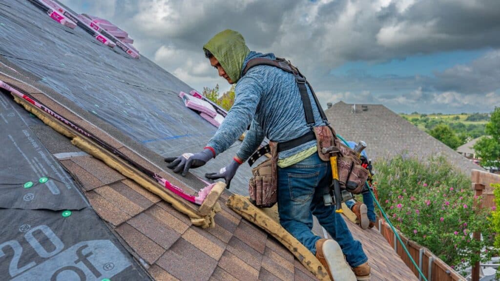 Roofers working on shingle installation on a home in Fort Worth, Texas under blue skies.