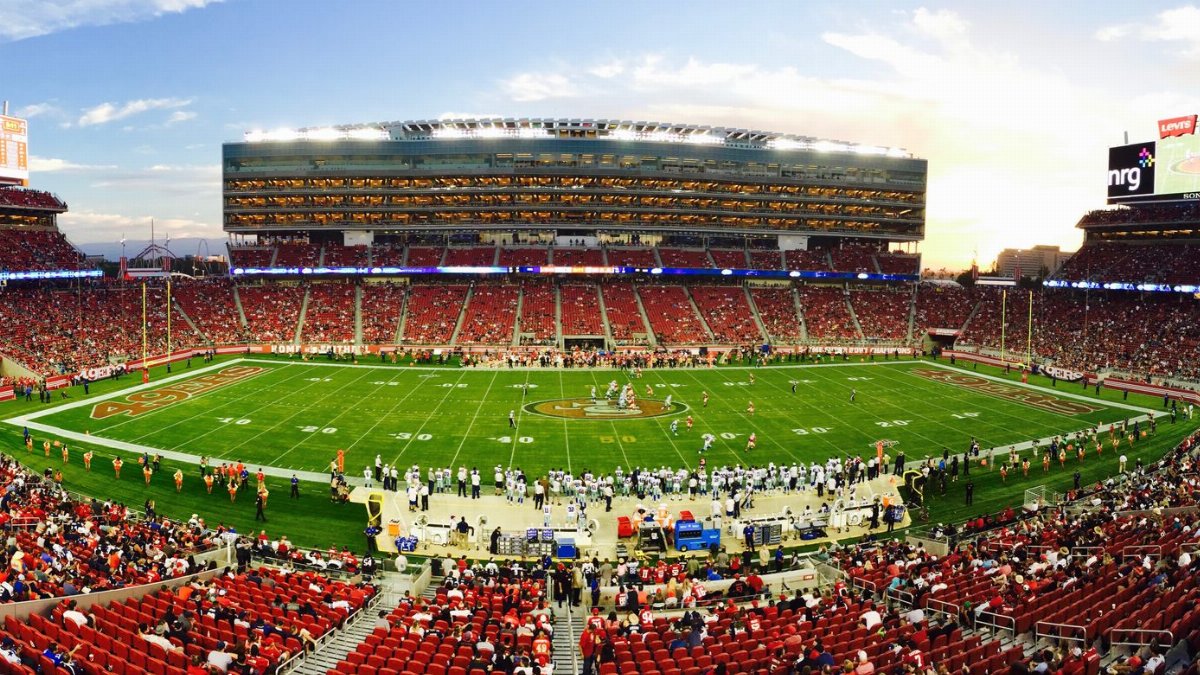 A stunning panoramic shot of Levi's Stadium in Santa Clara during a packed football game at sunset.