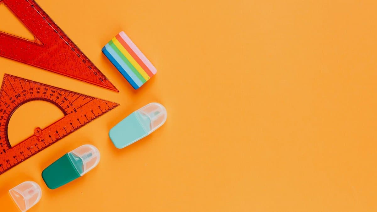 Vibrant flat lay of stationery items, including rulers and erasers, on an orange background.