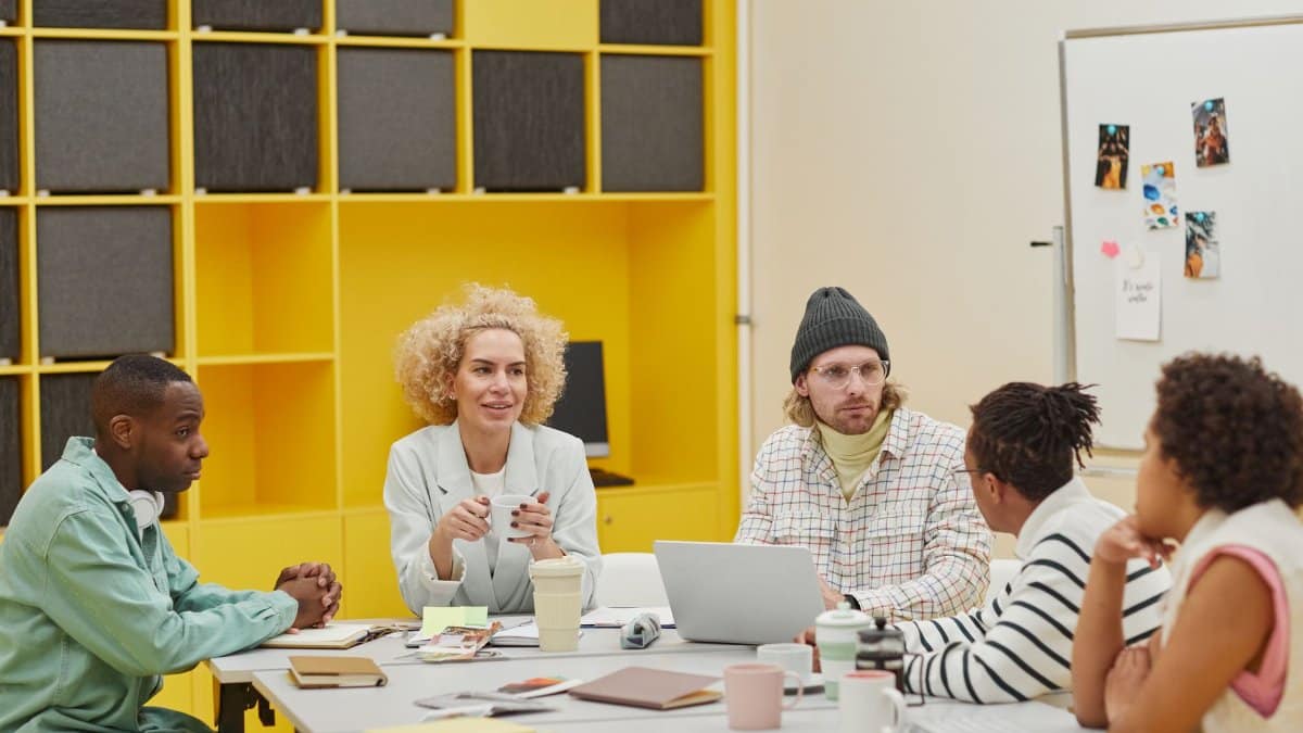 A diverse group of coworkers engaging in a meeting around a table in a modern office setting.
