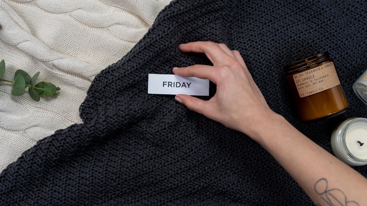 A warm, cozy flat lay featuring candles, a knitted blanket, and a 'Friday' tag, perfect for leisure or relaxation themes.