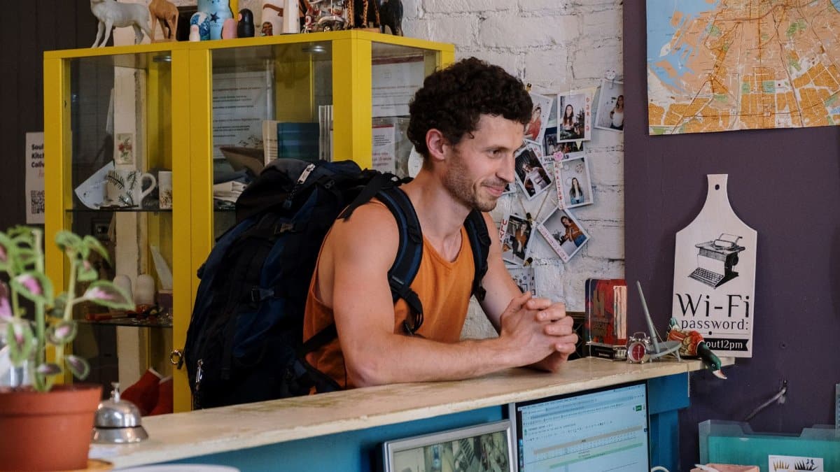 A backpacker checking into a cozy hostel with vibrant decor and friendly atmosphere.