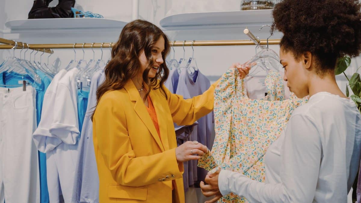 Two women engaging in a stylish clothing store, discussing fashion choices.