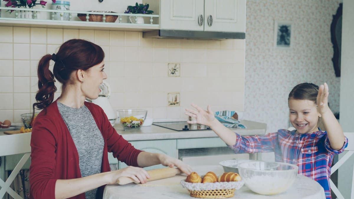 Mother and daughter joyfully baking in a cozy kitchen setting.