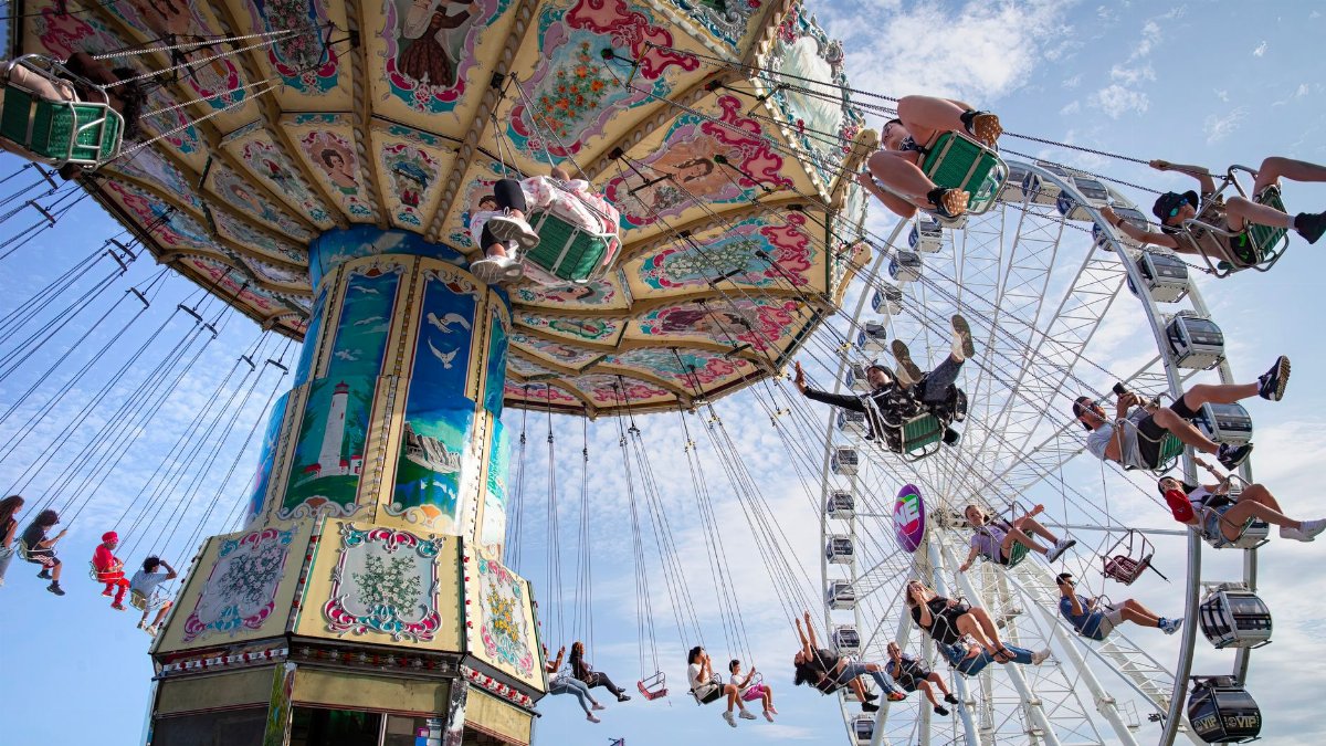 Exciting swing ride and Ferris wheel at a summer fair in Toronto, Canada.