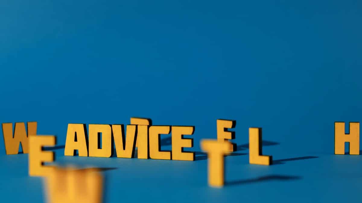 Wooden letters spelling 'Advice' on a blue background providing conceptual copyspace.