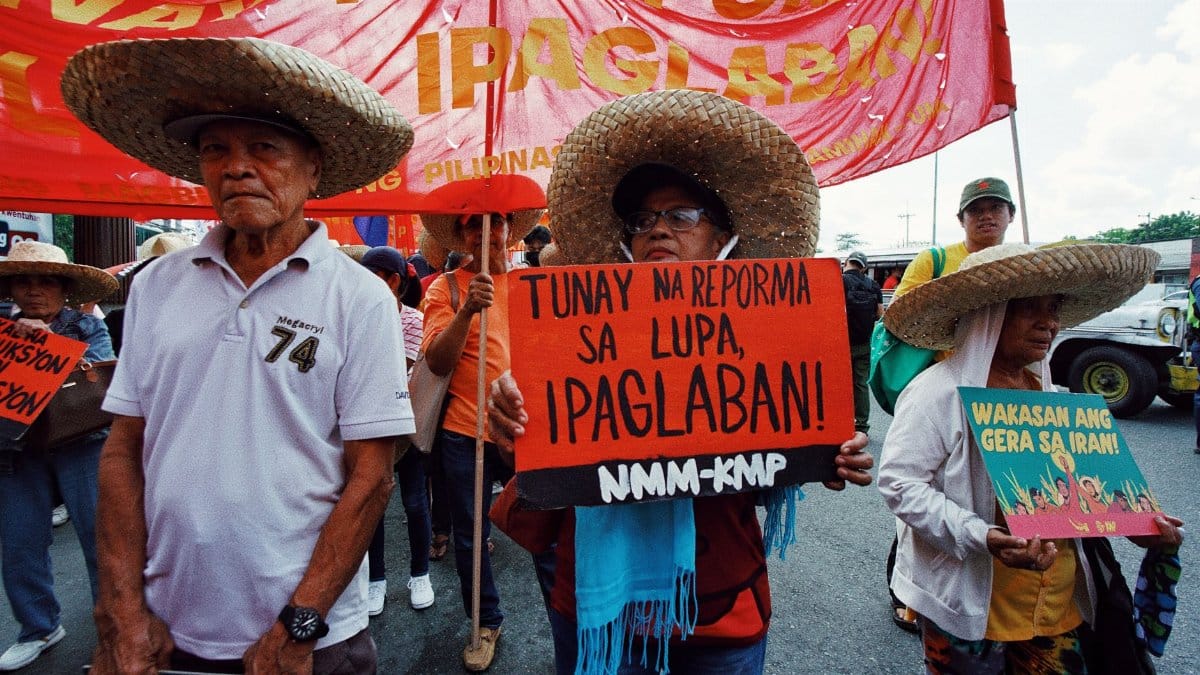 Filipino farmers protesting for land reform with colorful banners and traditional hats.