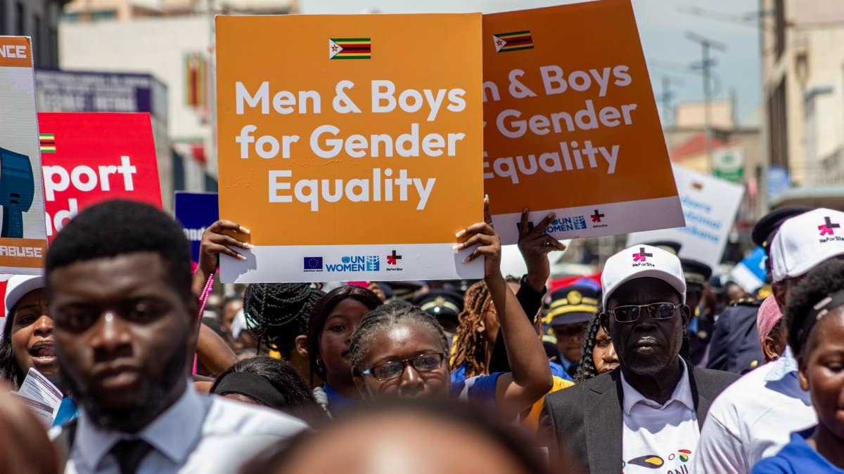 A vibrant crowd in Harare rallies for gender equality, holding signs promoting inclusion.