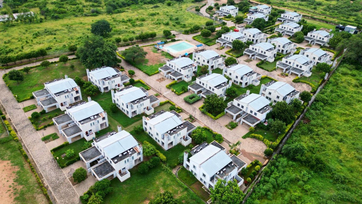 Aerial view of a modern residential neighborhood with white houses and green lawns.