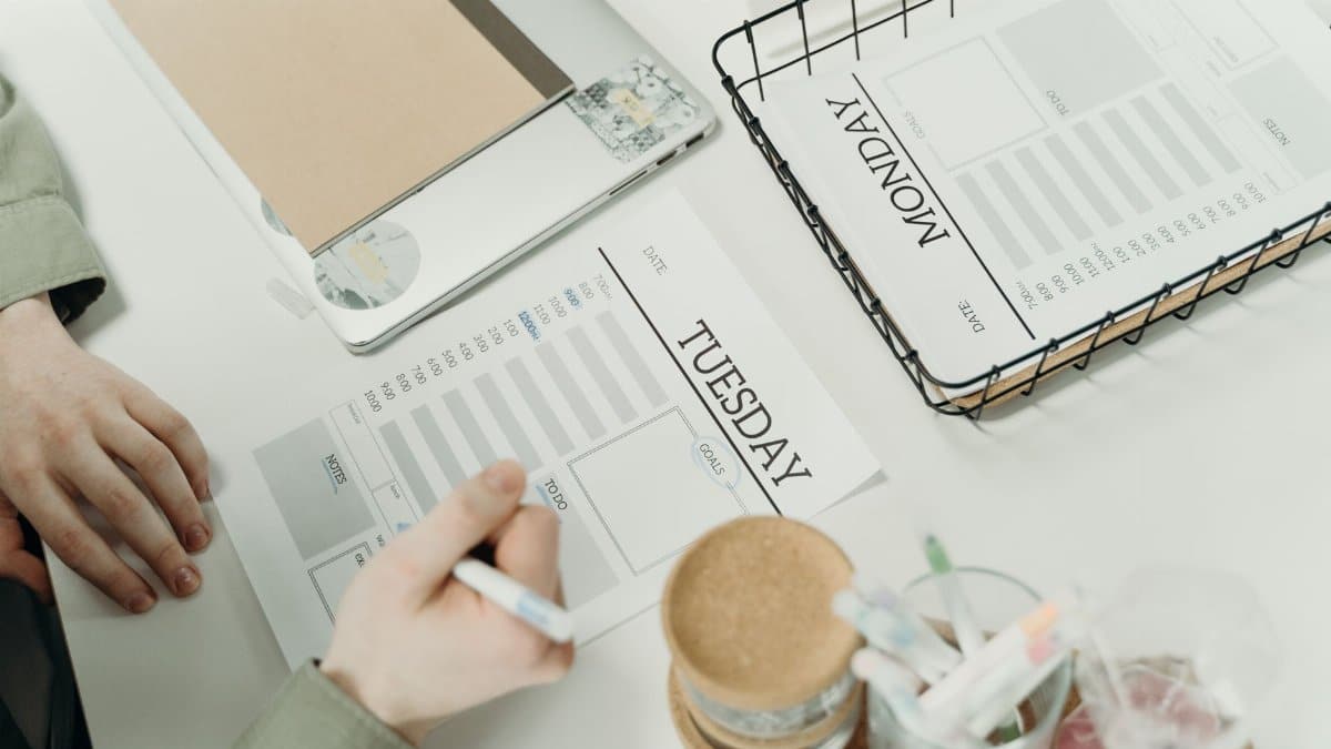 A professional organizing the week with detailed schedule planners in an office setting.