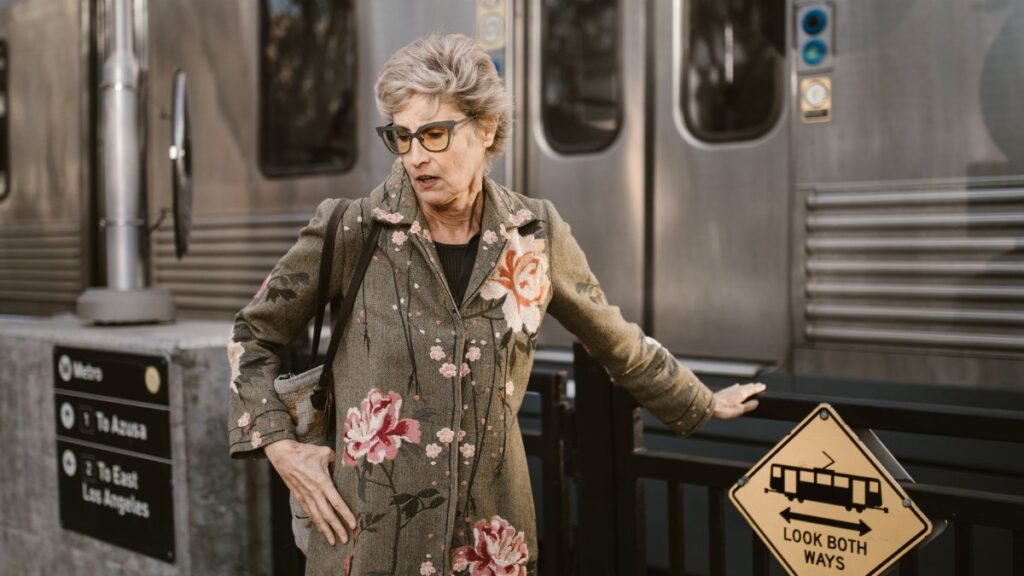 Elegant senior woman in floral coat waiting at Los Angeles metro station.