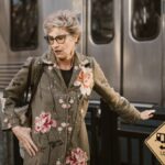 Elegant senior woman in floral coat waiting at Los Angeles metro station.
