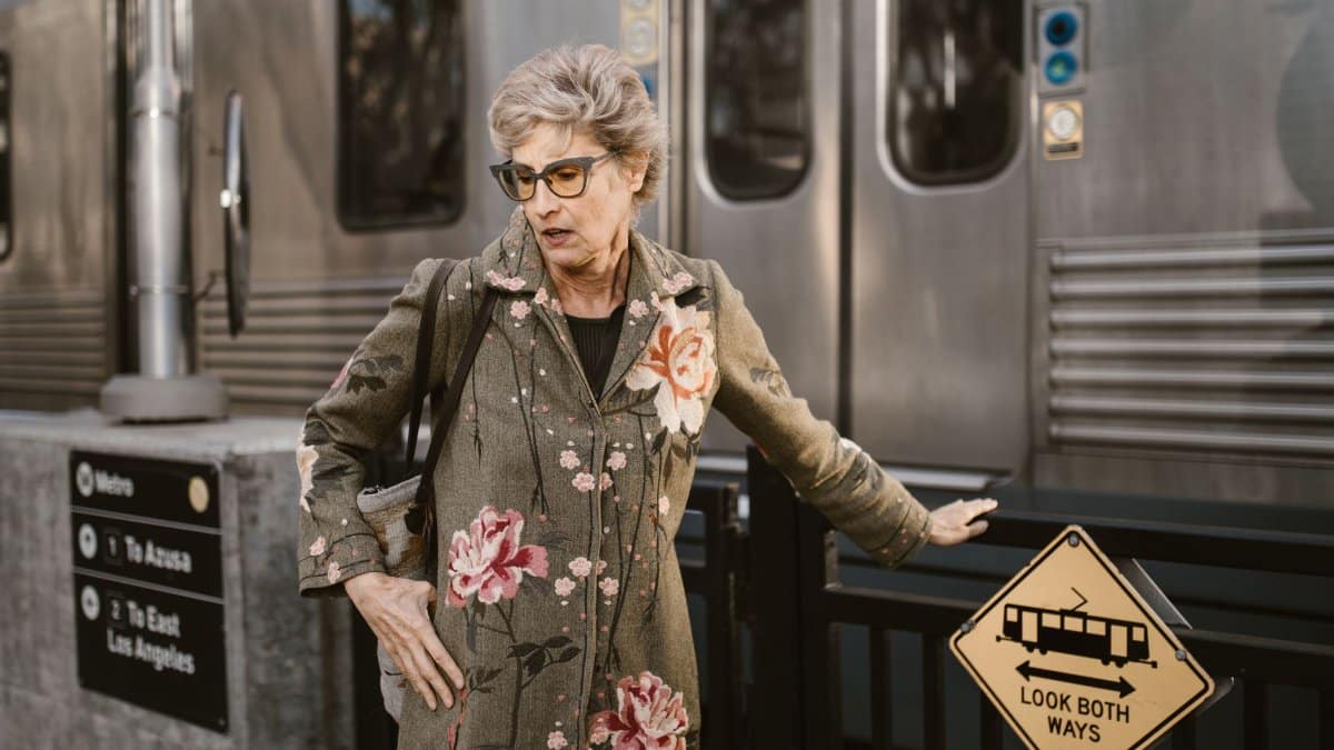Elegant senior woman in floral coat waiting at Los Angeles metro station.