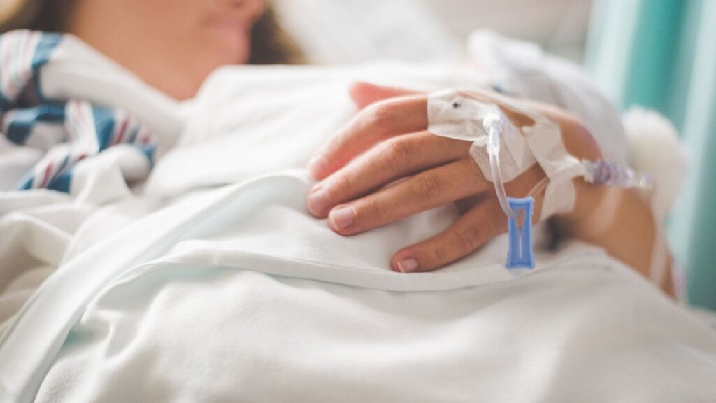 Focused shot of a patient's hand with IV in a hospital setting.