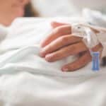 Focused shot of a patient's hand with IV in a hospital setting.