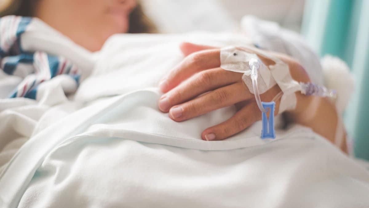 Focused shot of a patient's hand with IV in a hospital setting.
