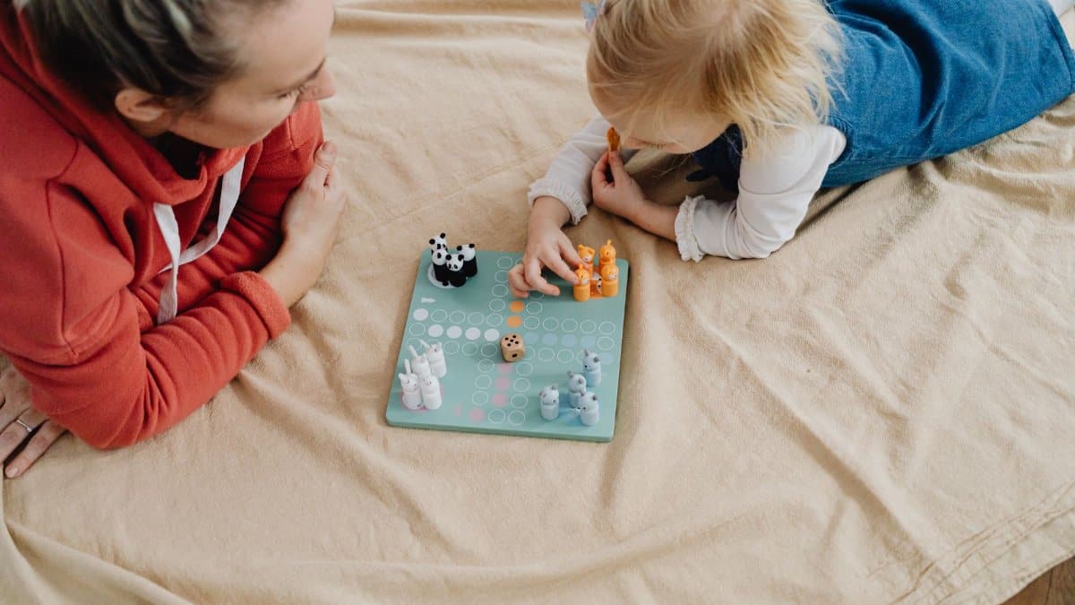 Mother and daughter enjoying a board game indoors, fostering connection and fun.