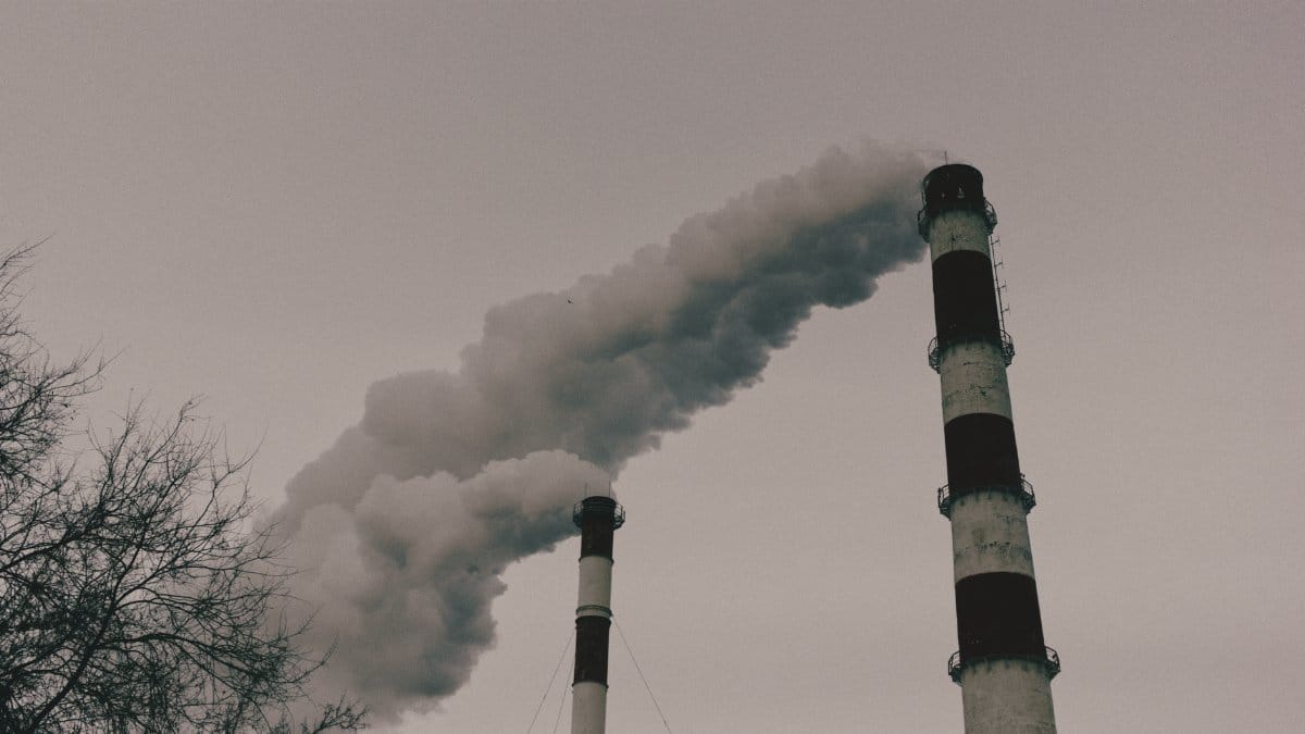 Environmental impact captured by smokestacks releasing plumes of smoke into the sky.