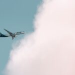 Alaska Airlines plane soaring through a bright sky with fluffy clouds in Seattle.