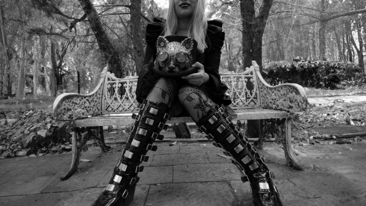 Black and white photo of a woman in gothic attire on a park bench in Mexico City.
