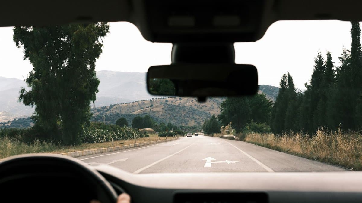 View from inside a car driving on a scenic, mountainous road during daytime.