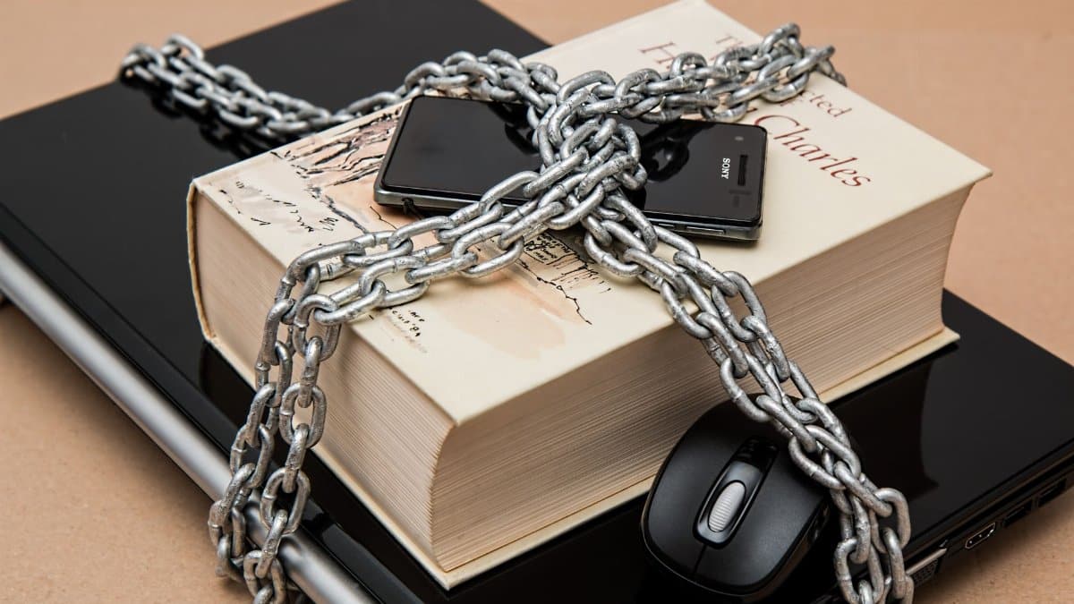 Chain-locked book, phone, and laptop symbolizing digital and intellectual security.