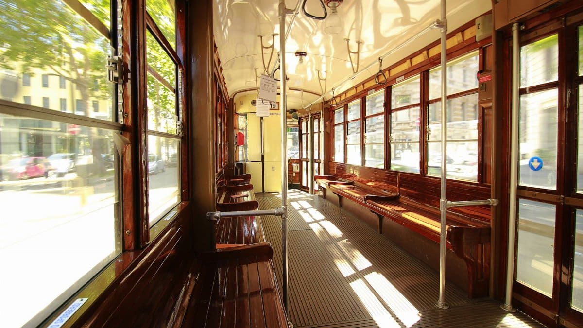 Capture of an empty vintage tram interior moving through a city during the day.
