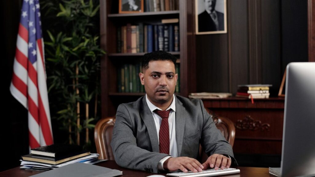 Corporate professional sitting at desk with American flag in office.