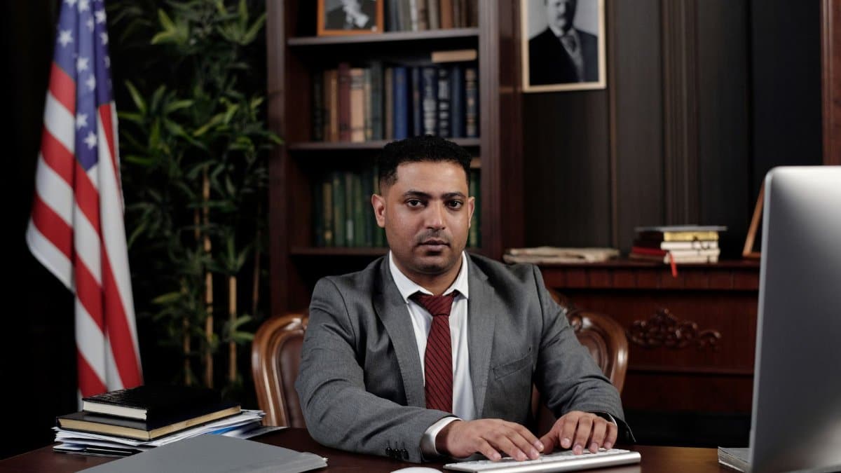 Corporate professional sitting at desk with American flag in office.